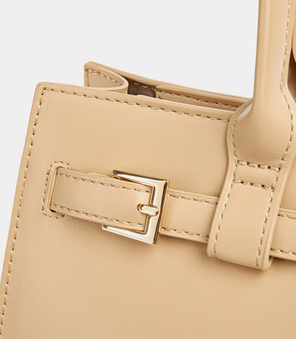 Close-up on the decorative buckle and stitching of the cream MOSSDOOM Aurelia bag.