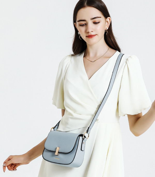 Model in a white dress wearing the MOSSDOOM AIRELLE shoulder bag, Sky Blue color.