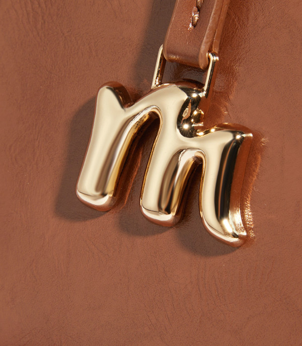 Close-up on the gold M charm of the MOSSDOOM REYNA shoulder bag.