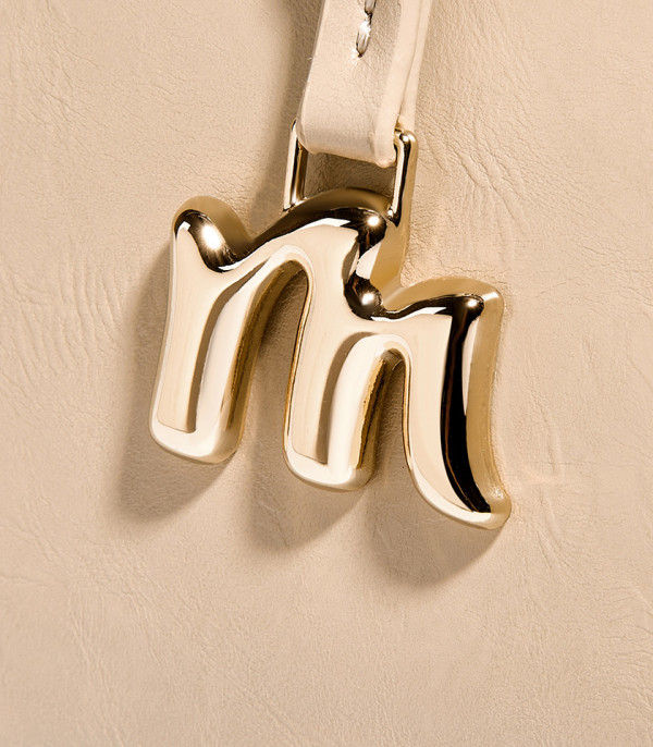Close-up on the gold M charm of the MOSSDOOM REYNA shoulder bag.