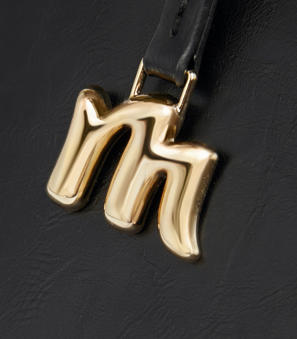 Close-up on the gold M charm of the MOSSDOOM REYNA shoulder bag.