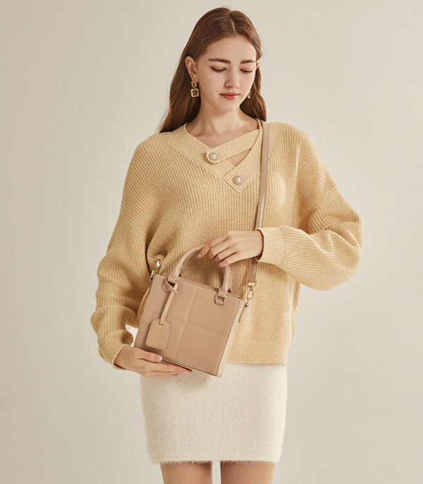 Model wearing the MOSSDOOM CUBIQUE structured handbag, Cream color.